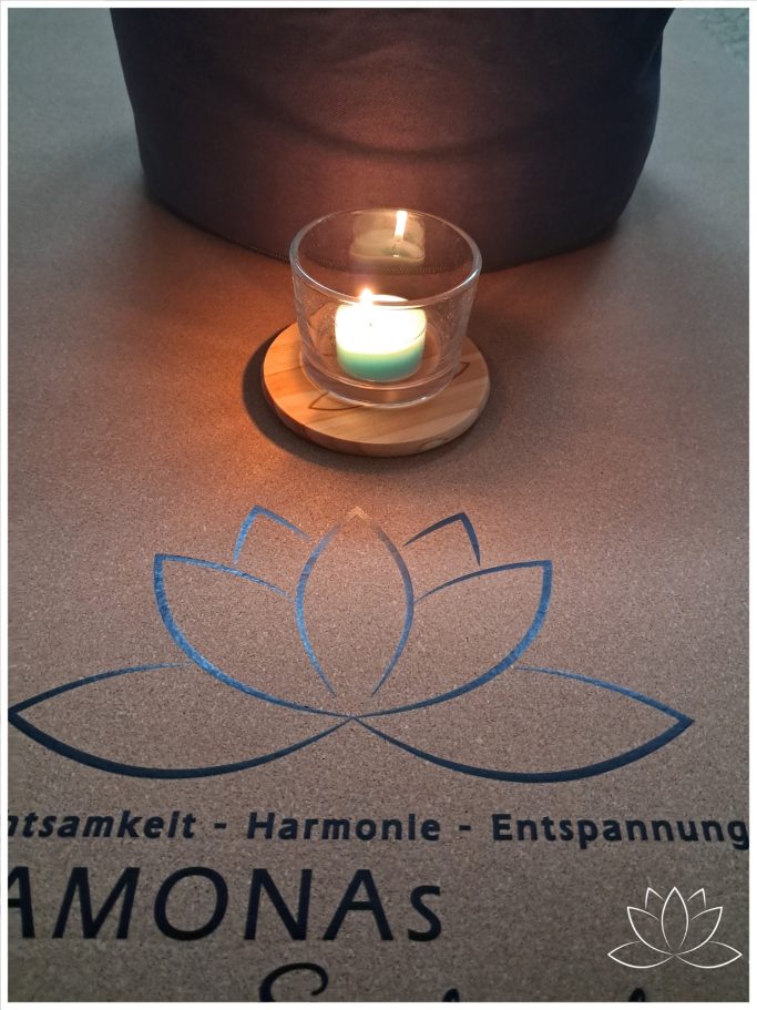 Kerze auf Holzuntersetzer vor einem Logo von Ramonas Seelenglück