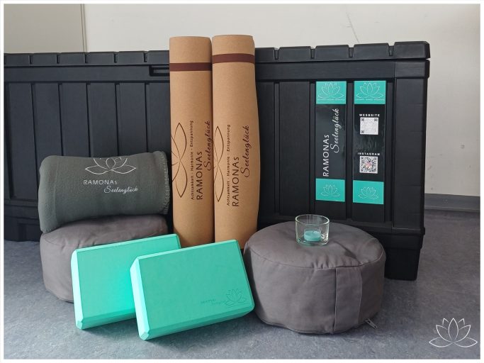Verschiedene Yogamatten und Kissen in einem Raum, darunter grüne und graue Accessoires.
