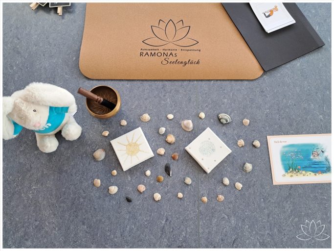 Ein Meditationsplatz mit Muscheln, kleinen Yoga-Bildern, einer Klangschale und Plüschhase Yon.