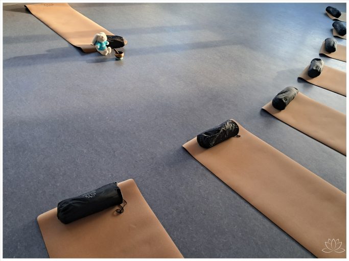 Yoga-Matten und Decken in einem Raum, ordentlich nebeneinander angeordnet.